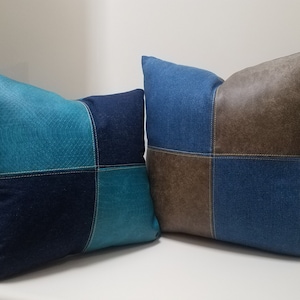 May include: Two decorative throw pillows with a patchwork design. The larger pillow is blue denim with brown faux leather accents. The smaller pillow is blue denim with teal faux leather accents.
