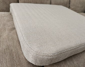 May include: A close-up of a beige cushion with a herringbone pattern. The cushion is made of a soft, textured fabric and has a subtle sheen.