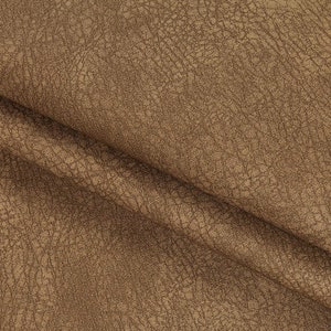 May include: Close-up of a brown faux leather fabric with a textured surface.