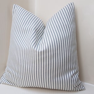 Puede incluir: Una almohada blanca con rayas azules. La almohada est&aacute; hecha de una tela suave y tejida y tiene un dise&ntilde;o simple y cl&aacute;sico.