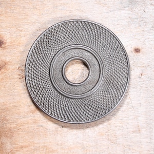Round shaped Cast iron trivet with hole in middle.