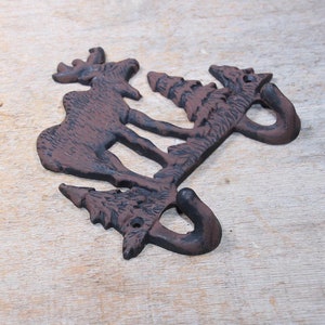 May include: A cast iron moose and pine tree wall hook with two hooks. The hook is painted in a dark brown color.