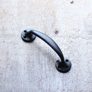 May include: Black metal door handle with a curved design and two round plates with screw holes.