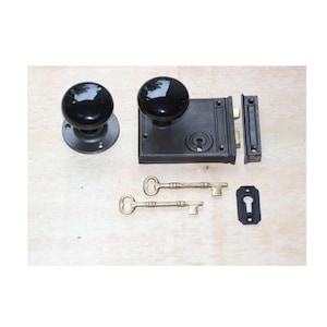 May include: A black door knob set with a matching latch, strike plate, and two keys. The door knobs are round and glossy. The set is made of metal, suitable for a vintage or antique door.