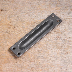 Peut inclure: Poignée de tiroir rectangulaire en métal noir avec une poignée ovale encastrée.