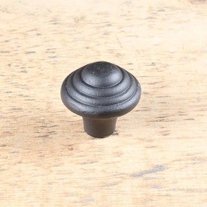 Peut inclure: Bouton de porte noir avec un dessus arrondi et un design à nervures.