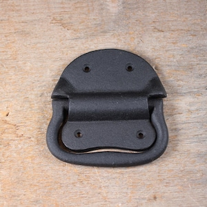 May include: Black metal handle with a rounded, rectangular shape. The handle has a smooth, matte finish and a slight curve in the center.