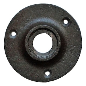 Op de afbeelding: Een cirkelvormige, donkergrijze metalen flens met een centraal gat en drie kleinere gaten. Het metaal heeft een ruw, getextureerd oppervlak, wat wijst op een industriële of vintage esthetiek.