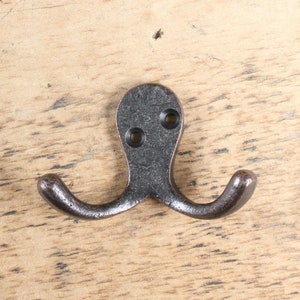 Peut inclure: Un crochet double en métal noir en forme de pieuvre. Le crochet est monté sur une surface en bois.