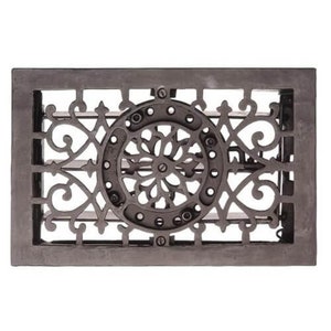Peut inclure: Une grille d'aération rectangulaire en fonte grise foncée avec un motif orné et symétrique. L'élément central est un motif circulaire avec un motif floral, entouré de volutes et d'un cadre rectangulaire.