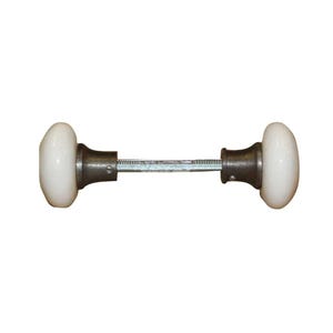 May include: A door knob set featuring two smooth, round white porcelain knobs attached to a central metal spindle. Each knob is connected to a dark, weathered metal base plate with a small visible screw on the side of the neck.