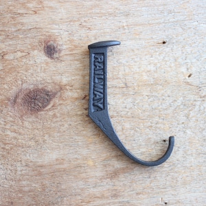 May include: A black metal hook with the word "RAILWAY" embossed on the front. The hook is shaped like a J and has a pointed end.