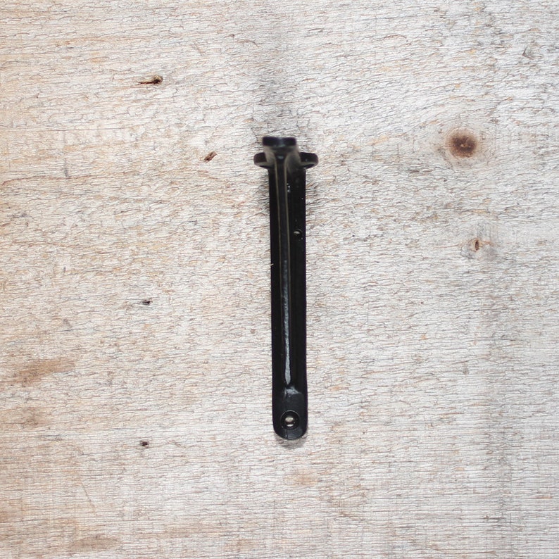 May include: Black metal shelf bracket with a simple design. The bracket is made of sturdy metal and has a smooth, black finish.