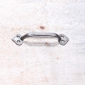 May include: A silver metal cabinet pull with a simple, curved design and two holes for mounting.