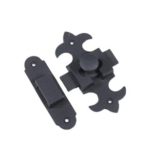 May include: Black metal latch with a decorative fleur-de-lis design. The latch has a small, round knob for opening and closing.
