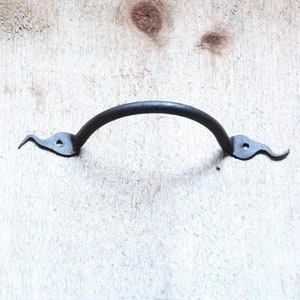 May include: Black metal door handle with a curved design and pointed ends.