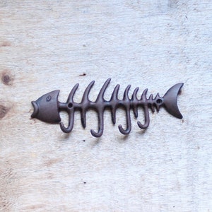 May include: A metal fish skeleton wall hook with five hooks. The hook is painted brown and has a realistic fish shape.
