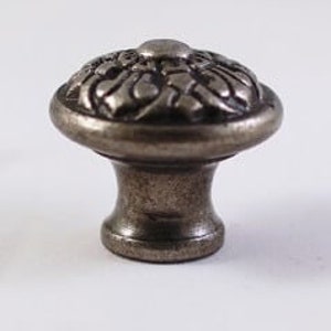 May include: A silver-toned metal cabinet knob with a decorative floral design.