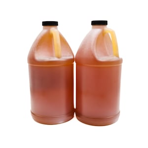 May include: Two clear plastic jugs with black lids and yellow handles filled with a light amber liquid.