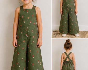 May include: An olive green jumpsuit featuring a repeating pattern of small red and white mushrooms. The garment has wide legs, a square neckline, and shoulder straps that cross at the back. Text on the image states: Model is a 3 year old girl, 38" tall, 33 lbs.