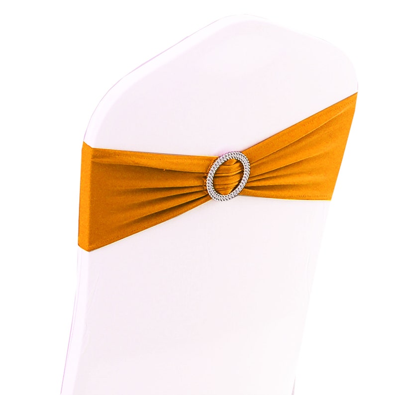May include: A gold chair sash with a clear rhinestone buckle. The sash is made of a stretchy fabric and can be used to decorate chairs for weddings, parties, or other special events.