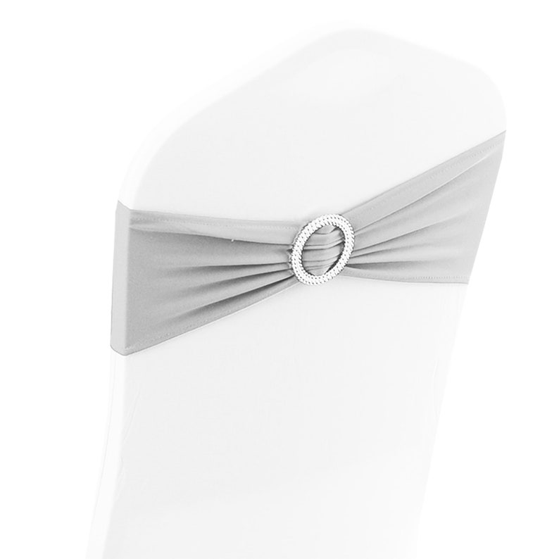 May include: Silver chair sash with a rhinestone buckle. The sash is tied in a bow around the back of a white chair.