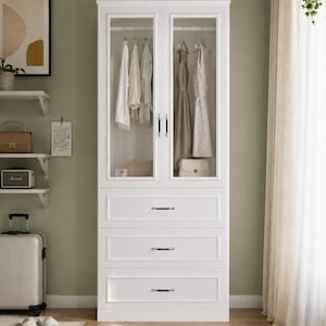 May include: A tall white wardrobe featuring two glass-paneled doors with vertical handles, revealing a hanging rod with clothing inside. Below the glass section are three stacked drawers, each equipped with a horizontal metal handle.