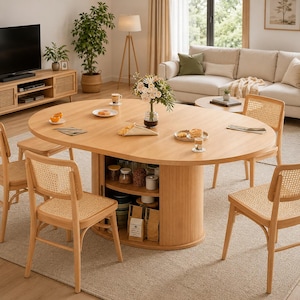 May include: A light wood oval dining table with a central pedestal base featuring integrated open shelving. The table is surrounded by four chairs with light wood frames and woven cane backrests. The tabletop holds a glass vase with flowers.
