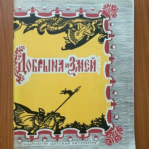 Pode incluir: Uma capa de livro vintage com fundo amarelo e ilustrações vermelhas e pretas. O título "Добрыня и Змей" está em escrita cirílica vermelha. A capa apresenta um cavaleiro a cavalo e um dragão. O nome da editora também é visível.