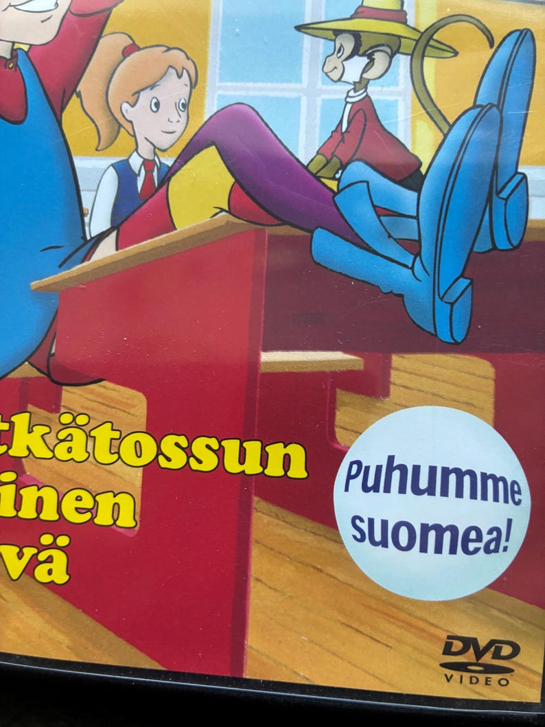 May include: DVD case featuring cartoon illustrations of a girl, a monkey, and a boy. The monkey wears a hat and red jacket. The text "Puhumme suomea!" is on a blue circle. The DVD logo is at the bottom.