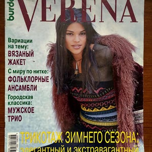 Op de afbeelding: De cover van het tijdschrift "Verena" toont een vrouw in een trui met patroon en een roodbruine, bontachtige jas. De titel van het tijdschrift staat in grote, vette letters. Er is ook tekst in het Russisch zichtbaar.