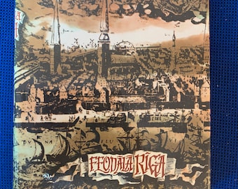 May include: A vintage book cover featuring a sepia-toned illustration of a city with tall spires, ships, and figures. The title "FEOÐALA RIGA" is prominently displayed. The cover has a historical and artistic aesthetic.