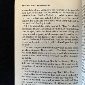 May include: An open book displaying text from "The Medieval Murderers". The text is in black on a cream-coloured page. The book is open to a page with multiple paragraphs of text.