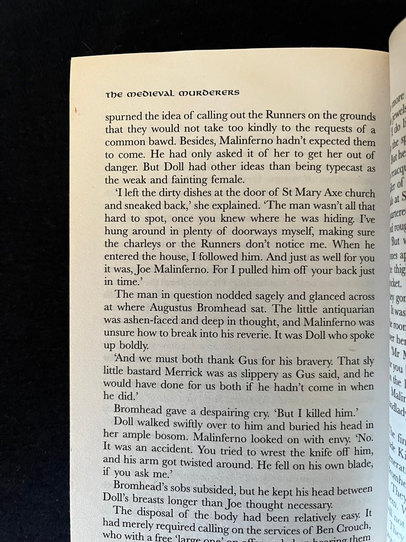 May include: An open book displaying text from "The Medieval Murderers". The text is in black on a cream-coloured page. The book is open to a page with multiple paragraphs of text.