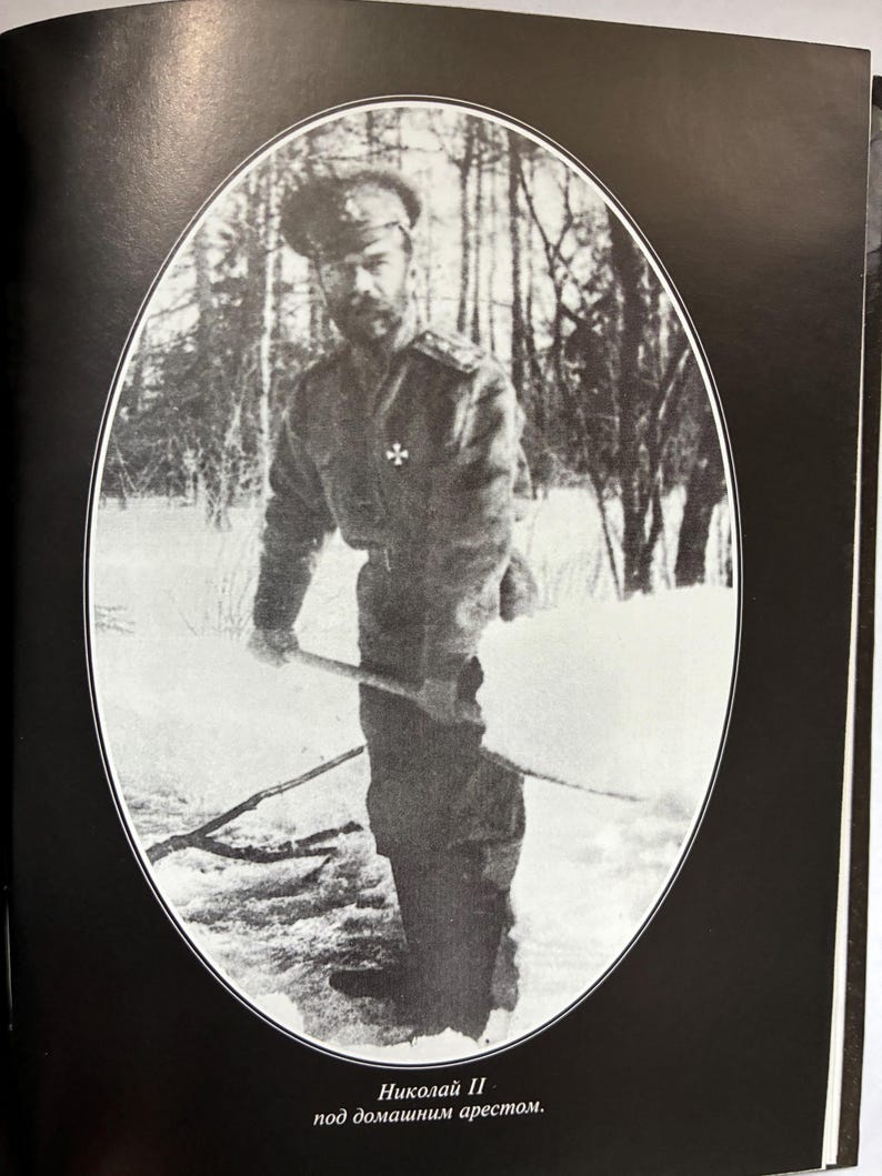 May include: Black and white photograph of a man in military attire, holding a stick, standing in a snowy outdoor setting. The image is framed in an oval shape. Text at the bottom reads "Nikolai II under house arrest."