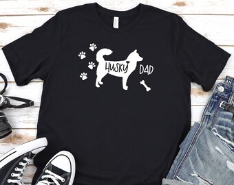 May include: Black t-shirt with a white silhouette of a husky dog and the text "Husky Dad" with a heart and a bone.