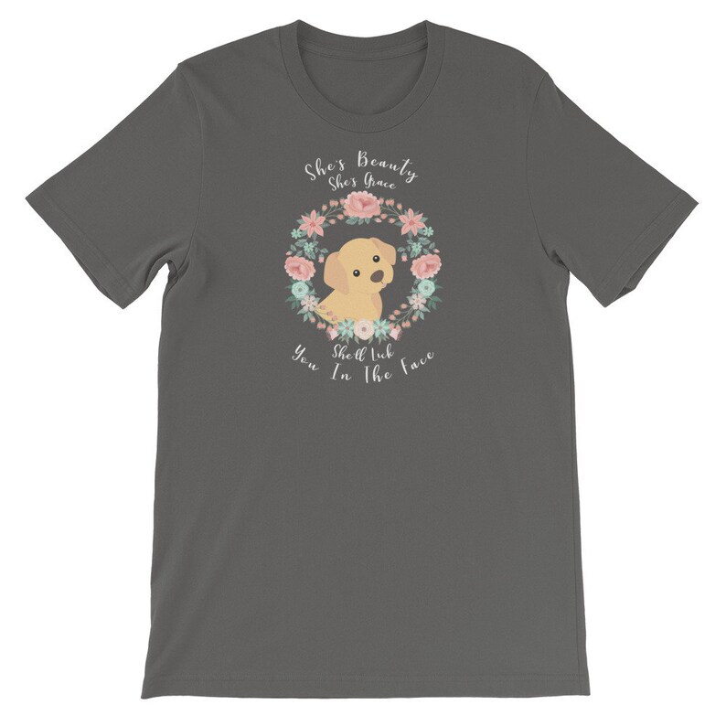 Puede incluir: Una camiseta gris oscuro con un dise&ntilde;o de corona de flores con un cachorro de labrador amarillo de dibujos animados. El texto "She's Beauty She's Grace She'll Lick You In The Face" est&aacute; impreso en la camiseta.