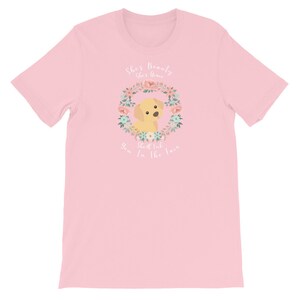 Puede incluir: Camiseta rosa con un gr&aacute;fico blanco de un perro en una corona de flores. El texto dice "She's beauty, she's grace, you'll  look in the face."