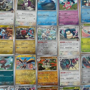 May include: A collection of colorful Pokémon trading cards, featuring various characters and card designs. The cards display character names, HP, and attack details, with a mix of vibrant illustrations and text.