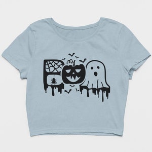 May include: A light blue short-sleeved crop top featuring a black graphic design that spells out the word BOO. The letter B contains a spider web and spider, the O is a jack-o'-lantern, and the second O is a ghost, with bats flying above.