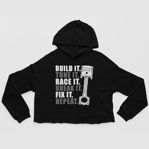 May include: Black cropped hoodie with a white graphic of a piston and the text "BUILD IT. TUNE IT. RACE IT. BREAK IT. FIX IT. REPEAT."