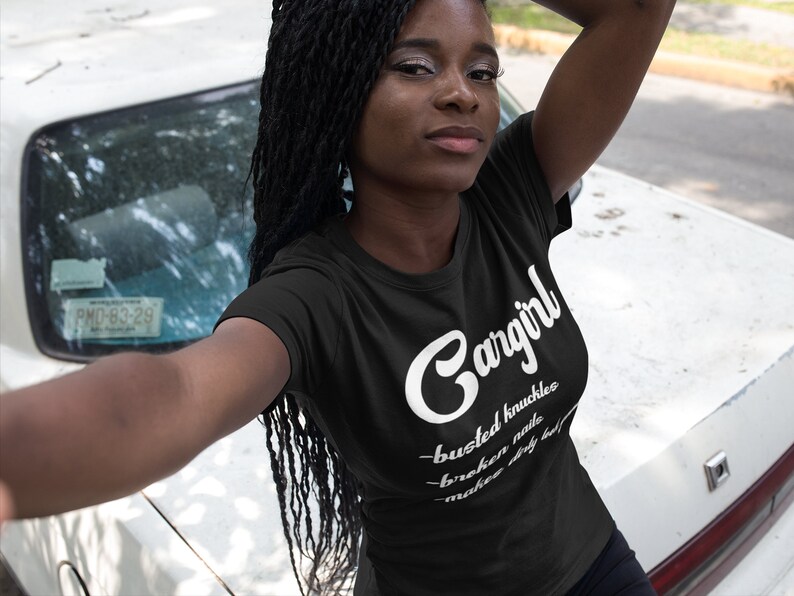 May include: Black t-shirt with white text that reads "Gangirl - busted knuckles - broken nails - make dirty look good".