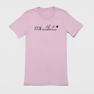 May include: A light pink t-shirt with the text "100% authentic" and a small black heart.