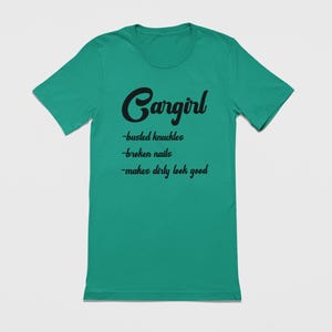 May include: A teal green t-shirt with black text that reads "Cargirl - busted knuckles - broken nails - makes dirty look good".