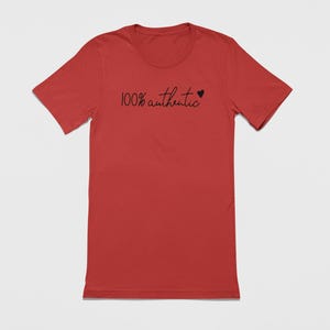 May include: A red t-shirt with the text "100% authentic" and a small heart symbol printed on the front.