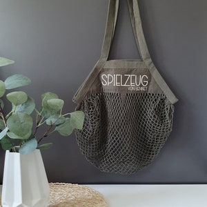 May include: A green canvas tote bag with a mesh bottom. The bag has a white embroidered label that says "Spielzeug von Bennet".