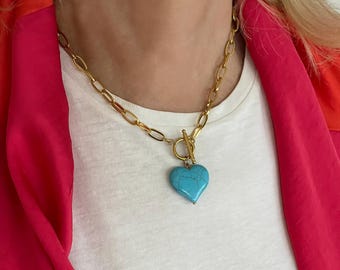 May include: Gold-toned chain necklace with a turquoise heart pendant. The necklace features a toggle clasp and a chunky link chain. The heart pendant is a vibrant shade of turquoise.