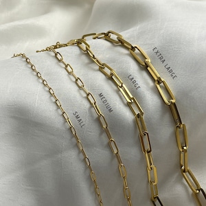 Peut inclure: Quatre colliers en chaîne dorés de différentes longueurs et tailles de maillons, étiquetés "Petit", "Moyen", "Grand" et "Très grand".