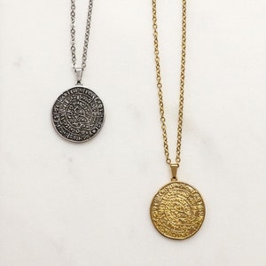 Peut inclure: Deux colliers avec des pendentifs circulaires. L'un est argent&eacute;, l'autre dor&eacute;. Les deux pendentifs pr&eacute;sentent un motif grav&eacute; et une cha&icirc;ne. Les colliers sont pr&eacute;sent&eacute;s sur fond blanc. Les pendentifs mesurent environ 2,5 cm de diam&egrave;tre.
