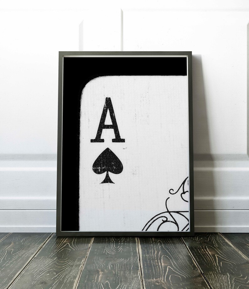 Op de afbeelding: Zwart-witte ingelijste print van een aas schoppen speelkaart met een verweerde, vintage look.